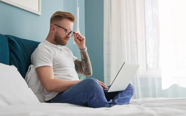 Mężczyzna freelancer za pomocą laptop na łóżko — Zdjęcie stockowe