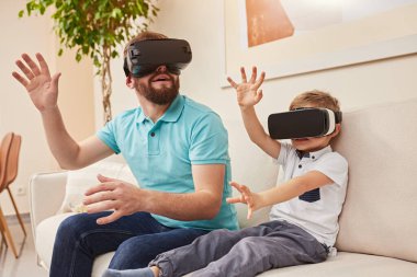 Baba ve oğul evde VR gözlüklü.
