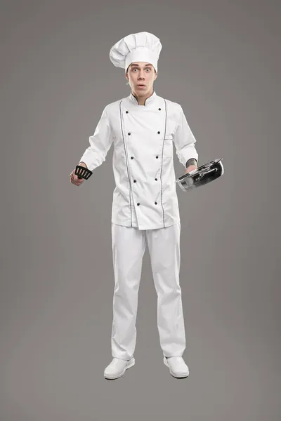 Puzzled young cook with kitchenware — Stock Photo, Image