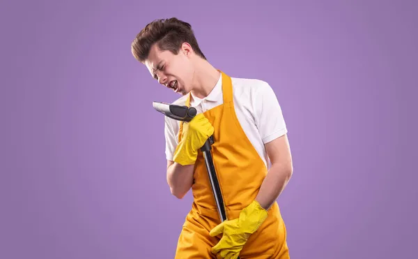 Young man singing into vacuum cleaner — Stock Photo, Image