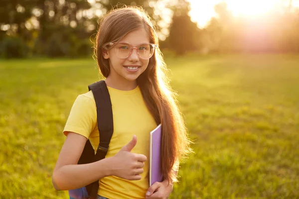 Tevreden tiener meisje tonen duim omhoog teken na studies in park — Stockfoto