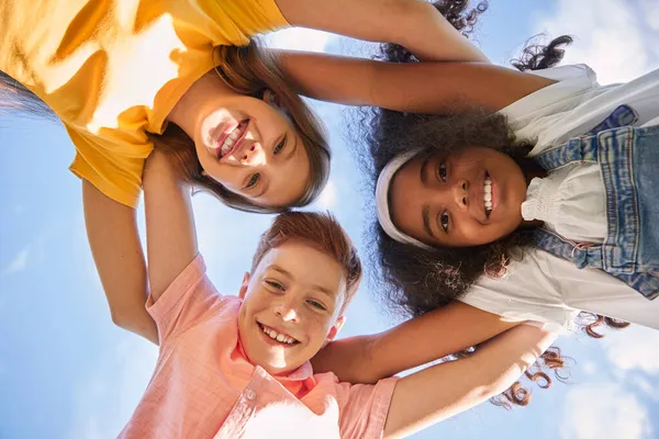 Niños felices abrazándose contra el cielo azul —  Fotos de Stock