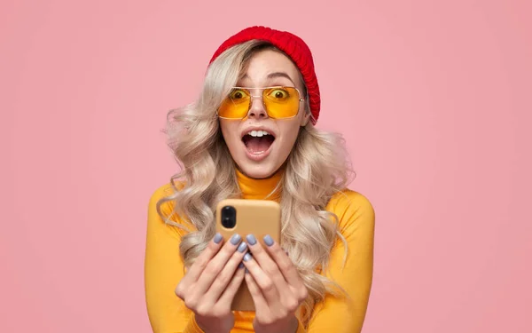 Σοκαρισμένη γυναίκα με πολύχρωμα γυαλιά ηλίου αντιδρώντας στο μήνυμα στο smartphone — Φωτογραφία Αρχείου