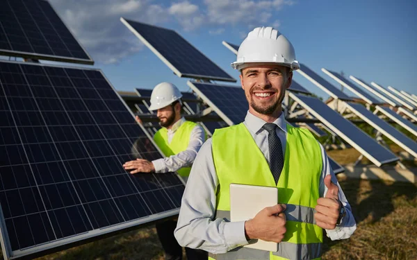 Felice caposquadra sorridente e mostrando pollice in su sulla centrale solare — Foto Stock