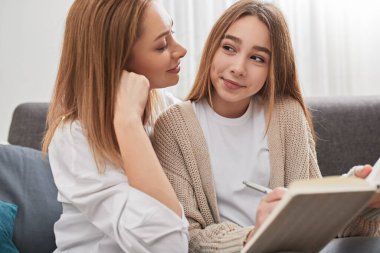 Anne, kızına ev ödevinde yardım ediyor.