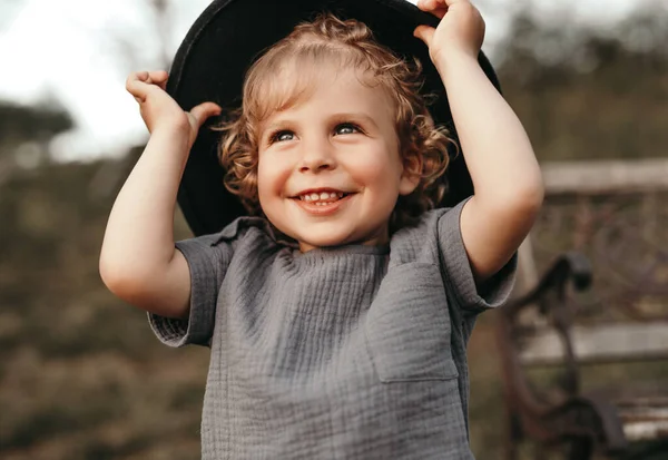 Menino feliz de chapéu em pé no campo — Fotografia de Stock