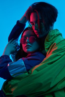 Stüdyoda neon ışıklarıyla kucaklaşan moda çift