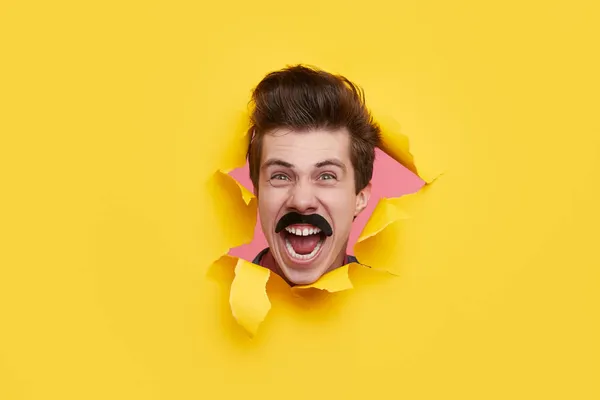 Hombre cómico con bigote a través de papel roto — Foto de Stock