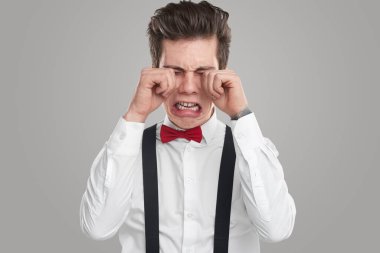 Resmi giyinmiş komik adam stüdyoda ağlıyor.