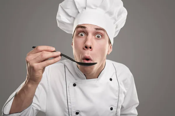 Funny cook blowing at spoon — Stock Photo, Image