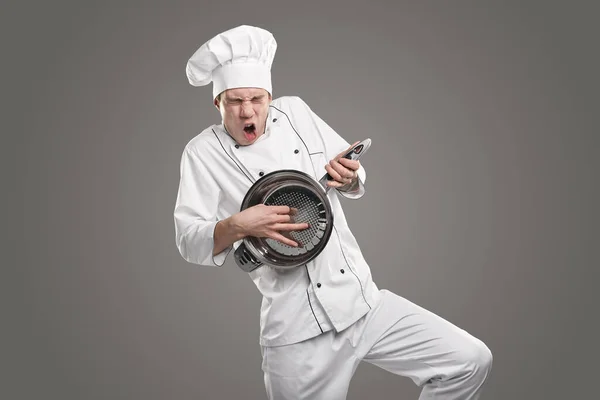 Expressive chef playing on colander like on guitar — Stock Photo, Image