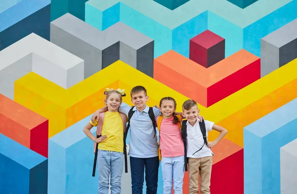 Schoolkinderen omarmen tegen kleurrijke muur — Stockfoto