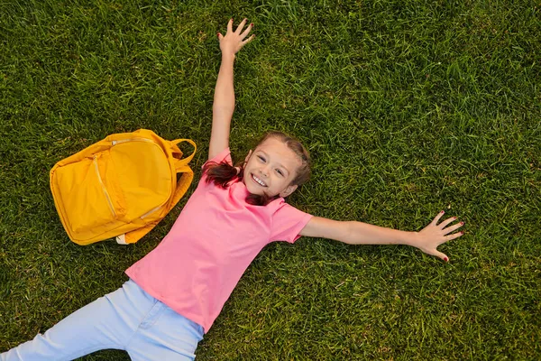 Lachend schoolmeisje liggend op gras tijdens de pauze — Stockfoto