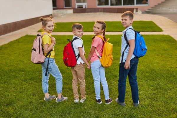 Schoolkinderen met rugzakken op groene tuin — Stockfoto