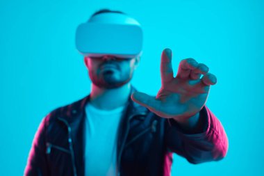 VR gözlüklü adam sanal gerçeklikte havaya dokunuyor.