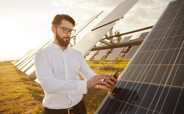 Homem controlando painéis solares via smartphone — Fotografia de Stock