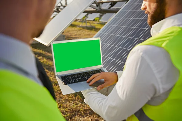 Engineers using laptop in field with solar panels — Stock Photo, Image