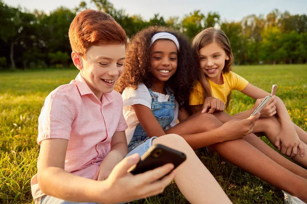 Різноманітні діти використовують смартфон разом — стокове фото