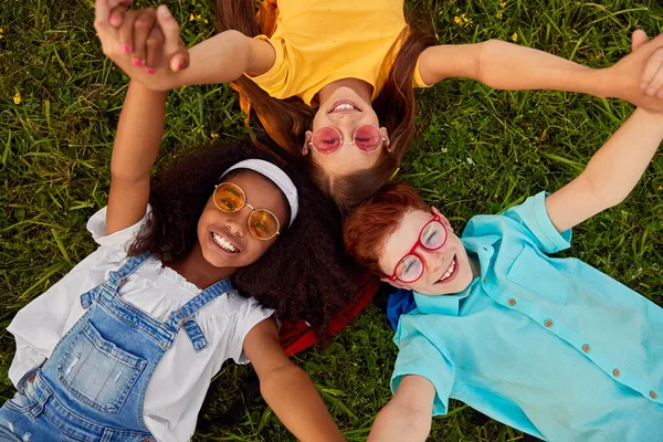 Diverse gelukkige kinderen liggen in cirkel op gras — Stockfoto