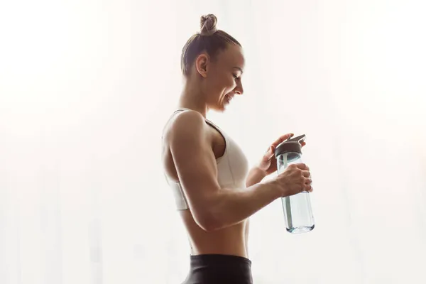 Cheerful female athlete drinking water — Stock Photo, Image