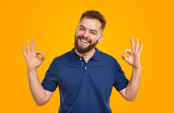 Glimlachende man met OK-tekens op gele achtergrond — Stockfoto