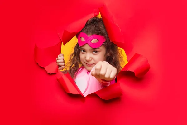 Потужна супергеройська дівчина розриває червоний паперовий фон — стокове фото