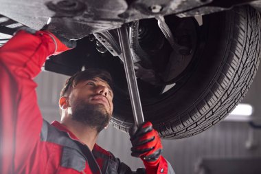 Tamirci atölyede araba şasisi tamir ediyor.