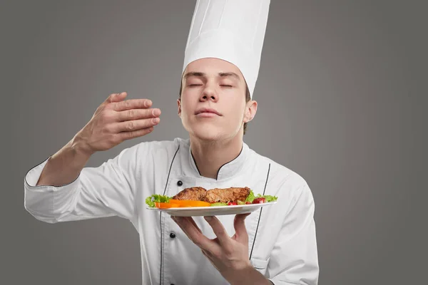 Satisfied chef smelling dish on plate — Stock Photo, Image