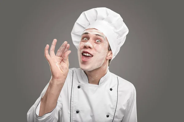 Gek jong mannetje bakker met bloem op gezicht gebaren op camera — Stockfoto