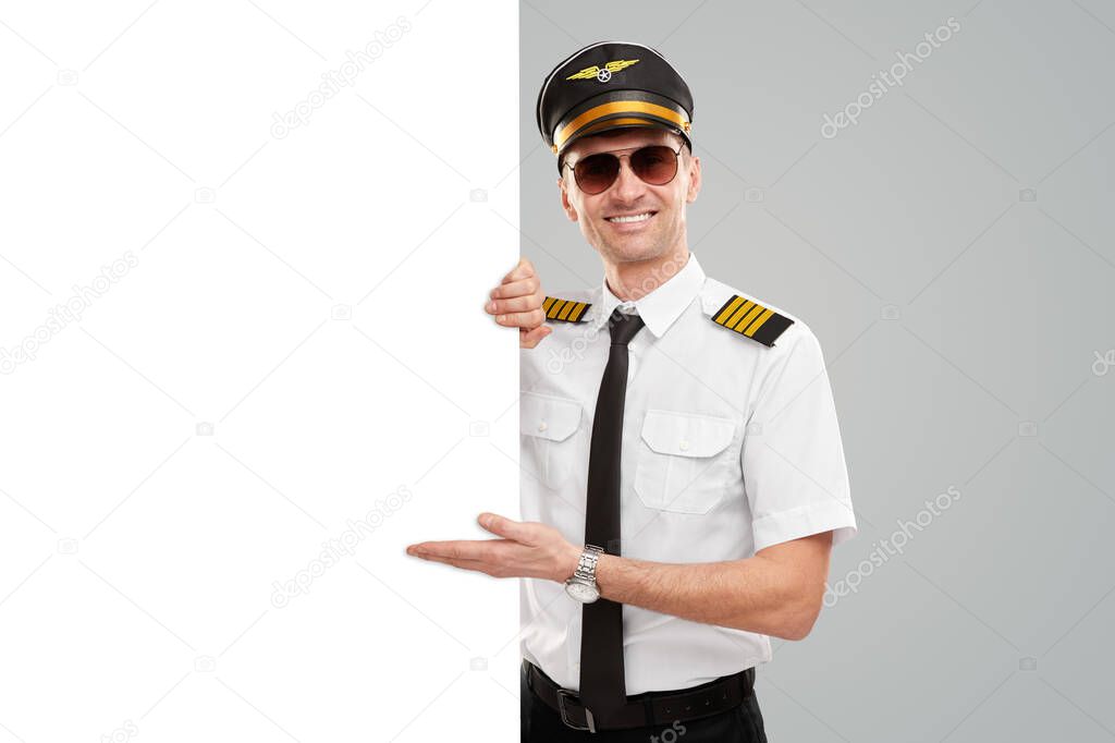 Cheerful pilot pointing at blank banner