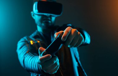 VR gözlüklü ve joystick 'li bir adam video oyunu oynuyor.