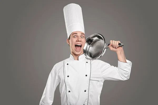 Εκφραστικό νεαρό αρσενικό σεφ με τηγάνι στο χέρι φωνάζοντας στην κάμερα — Φωτογραφία Αρχείου