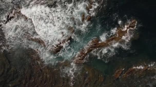 Zicht vanuit de lucht op golven die op vulkanische kustlijn verpletteren — Stockvideo