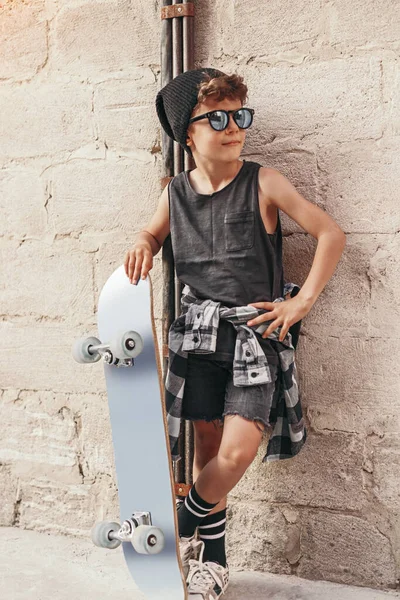 Fashionable boy with skateboard in city — Foto de Stock
