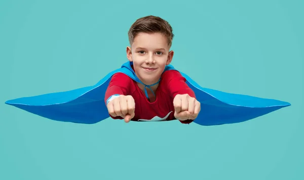Positive little superhero boy imitating flight in bright studio — Stock Fotó