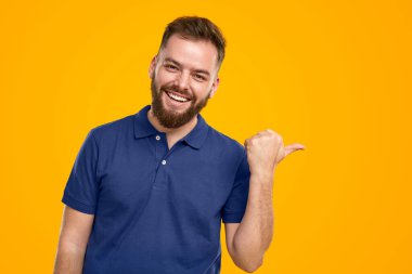 Happy man pointing aside in studio