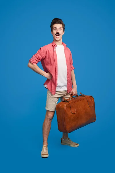 Funny traveling man with suitcase in studio — Stockfoto