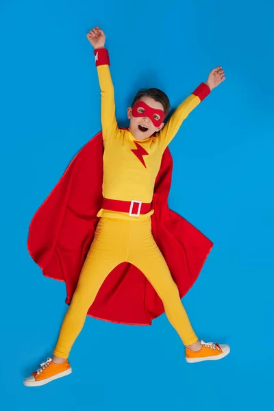 Cheerful superhero child in costume in studio — Stock fotografie