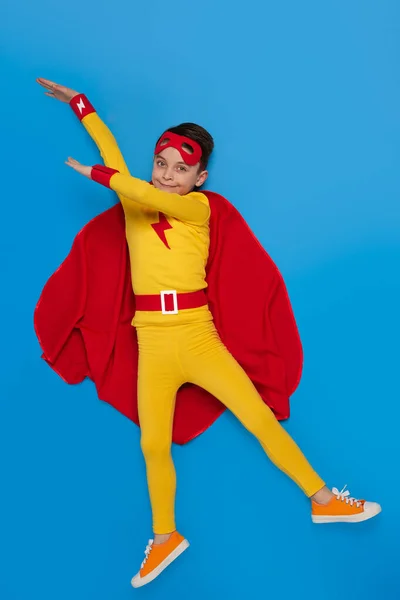 Superhero kid in costume pointing away in studio — Stock fotografie