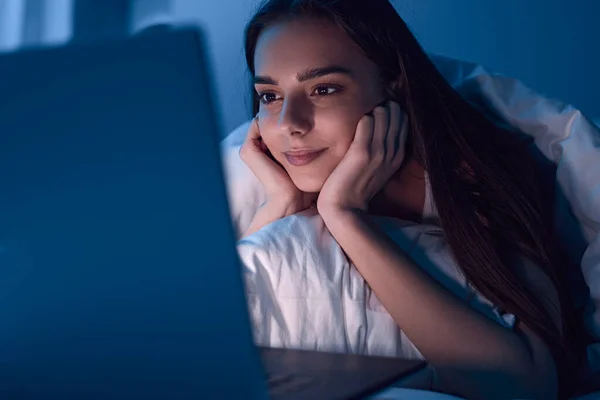 Content woman watching movie on laptop at night — Stock Fotó