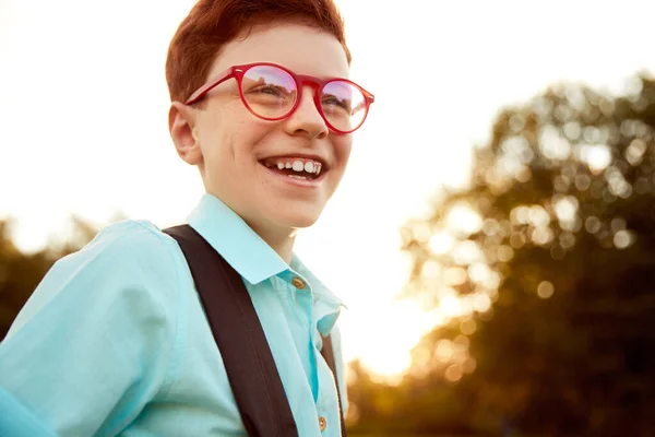 Mądry rudy chłopiec w okularach w parku — Zdjęcie stockowe