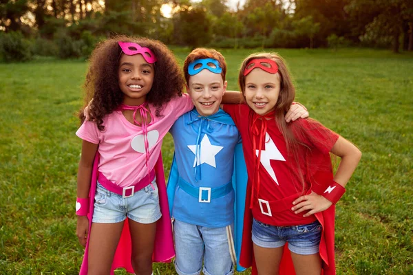 Feliz diverso superhéroe niños abrazándose en el parque de verano —  Fotos de Stock