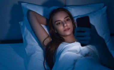 Gece geç saatlerde cep telefonu kullanan genç bir kadın.