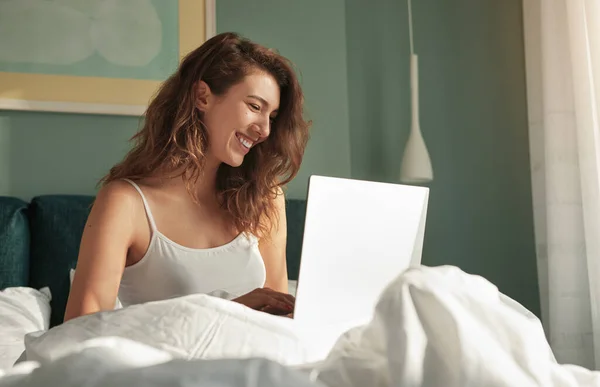 Ευτυχισμένη γυναίκα που χρησιμοποιεί φορητό υπολογιστή στο κρεβάτι — Φωτογραφία Αρχείου