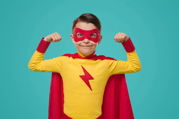 Süper kahraman kostümlü güçlü çocuk pazılarını gösteriyor. — Stok fotoğraf