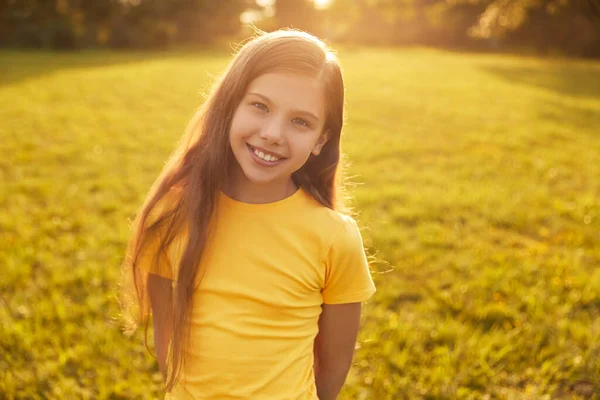 Усміхнена дівчина дивиться на камеру в парку — стокове фото