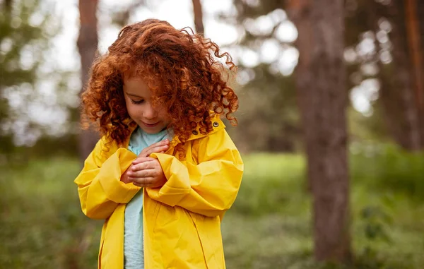 Menina ruiva em capa amarela na floresta — Fotografia de Stock