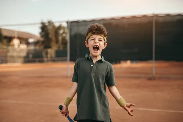 Захоплений хлопчик святкує перемогу на тенісному корті — стокове фото
