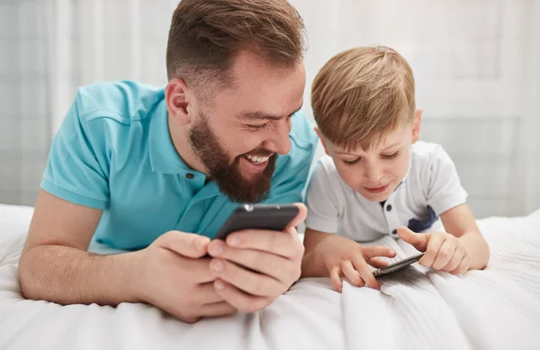 Отец и сын используют смартфоны вместе — стоковое фото