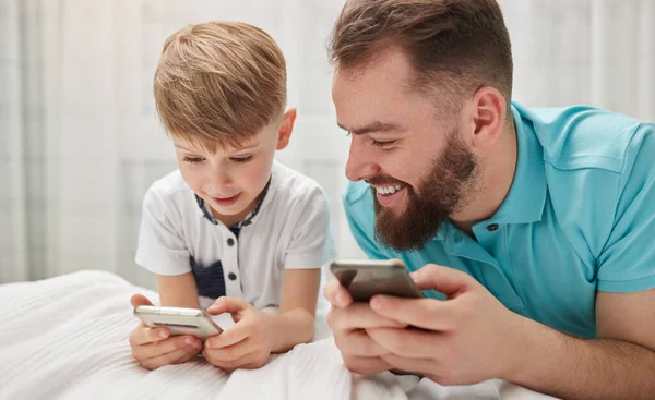 Vader en zoon spelen videogame op smartphones — Stockfoto